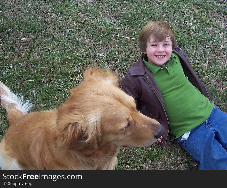 Golden retrievre and young boy playing in field in winter. Golden retrievre and young boy playing in field in winter