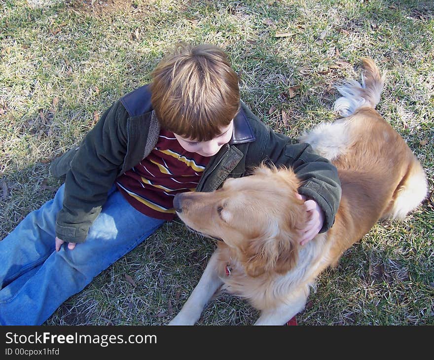 View from above of young boy and pet golden retriever in grassy field. View from above of young boy and pet golden retriever in grassy field