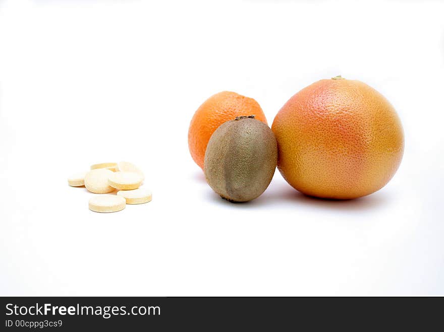 Fresh fruits versus pills, on white surface