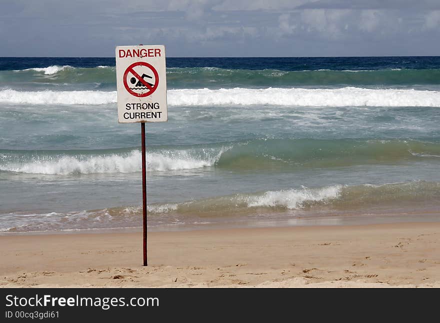 Danger Sign In Front Of Breaking Pacific Ocean Waves At A Sydney Beach, Australia