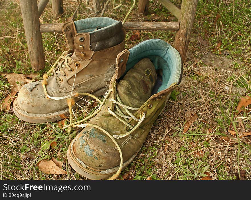 Pair of old work boots against old chair. Pair of old work boots against old chair