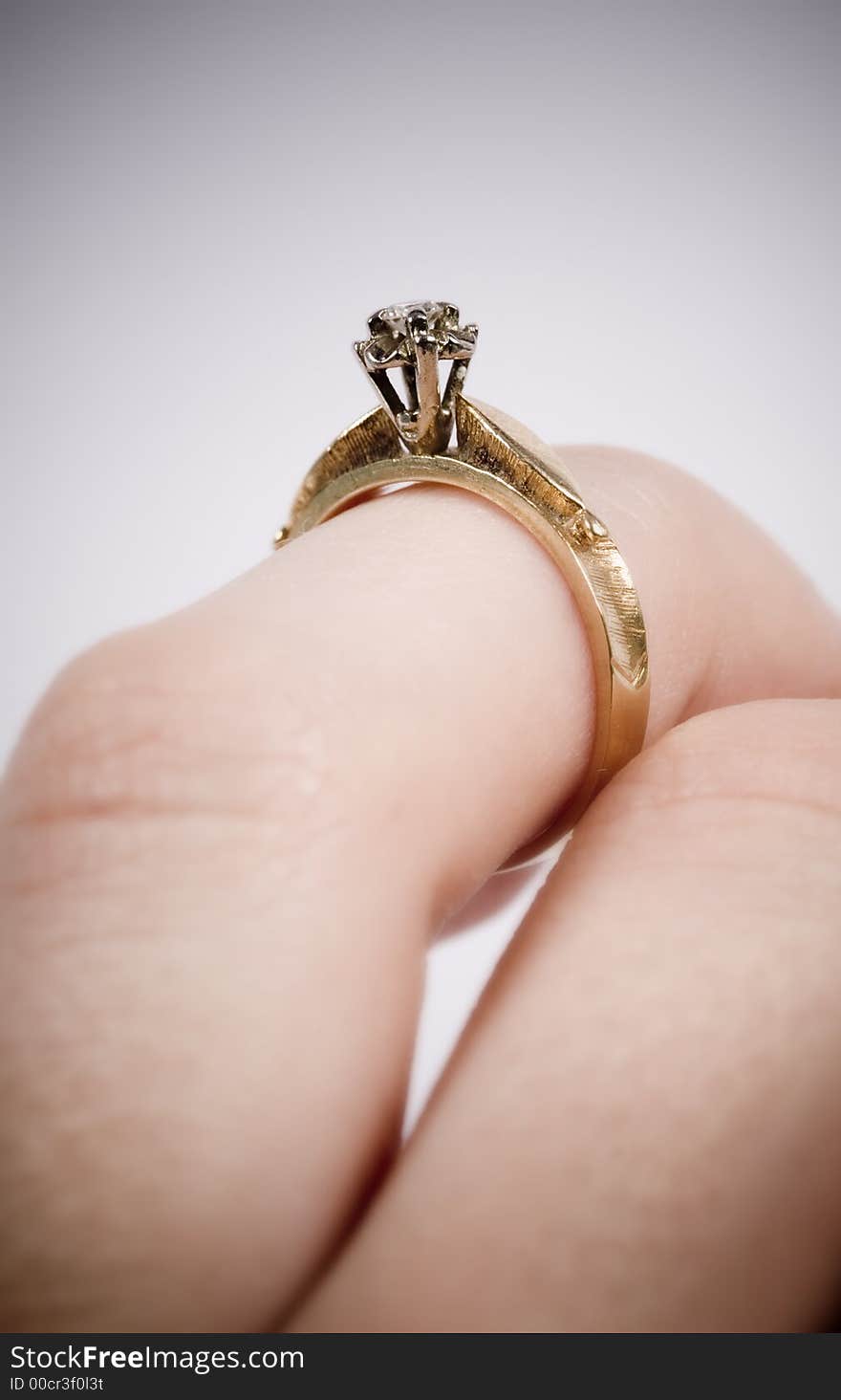 Woman putting on a gold engagement ring