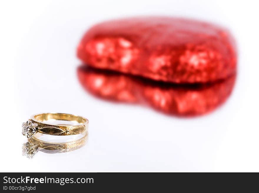 A gold engagement ring with heart on white