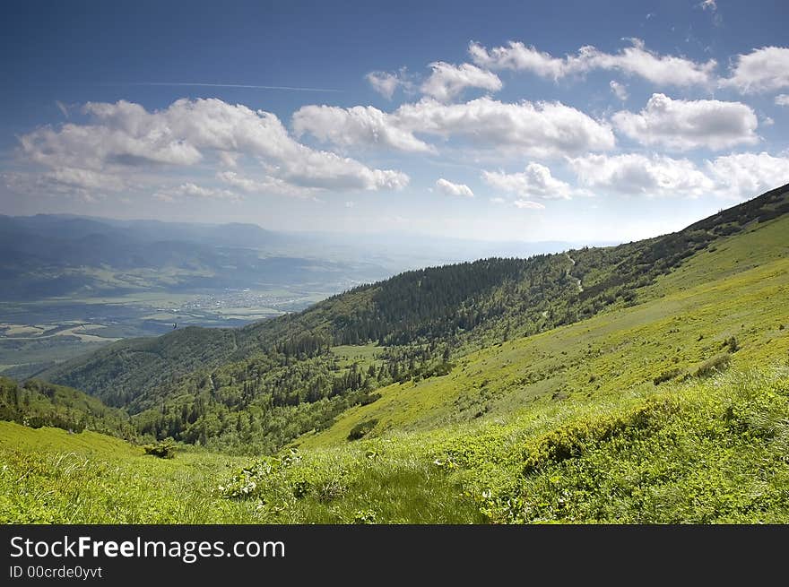 Mountain landscape - green filed, the blue sky and white clouds. Mountain landscape - green filed, the blue sky and white clouds