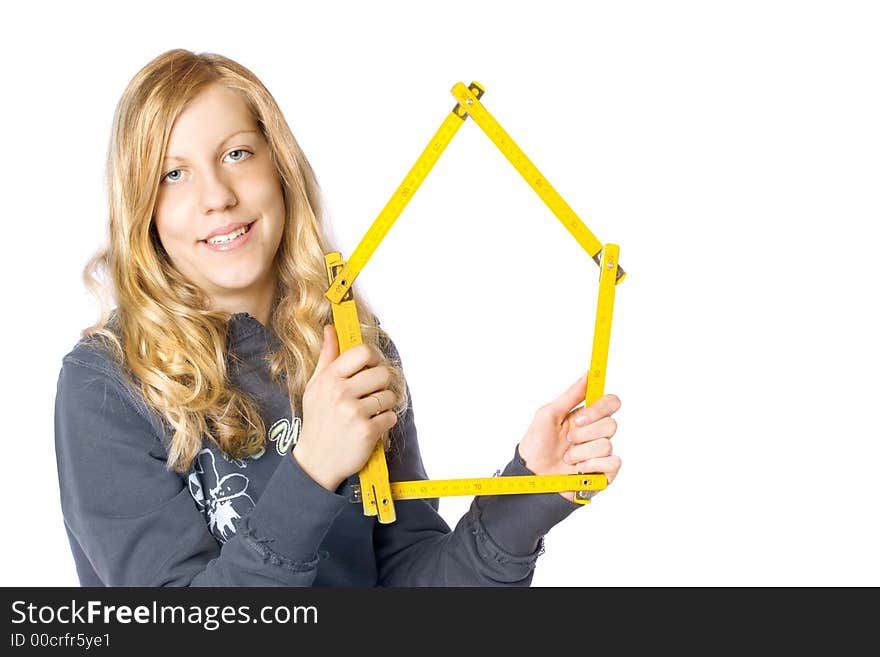 Young girl holding a metre measure (notice a house shape) near her face. A concept of a new house or a renovation. Young girl holding a metre measure (notice a house shape) near her face. A concept of a new house or a renovation.