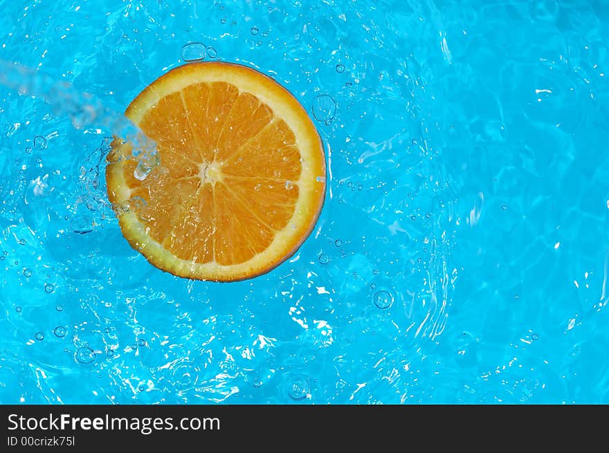 Water splashing on orange in blue water. Water splashing on orange in blue water