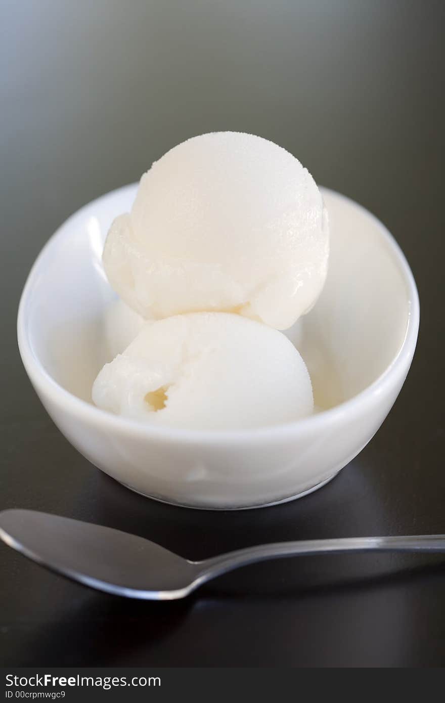 Three Scoops of Lemon Sorbet with a spoon on a table. Three Scoops of Lemon Sorbet with a spoon on a table