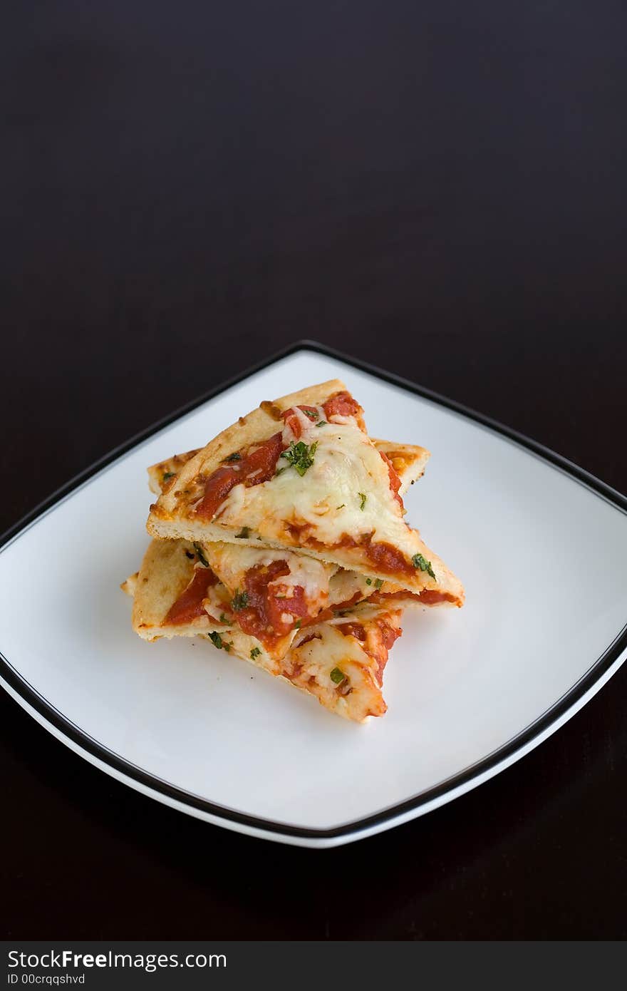 Small slices of plain pizza stacked on a white plate. A quick easy lunch. Small slices of plain pizza stacked on a white plate. A quick easy lunch.