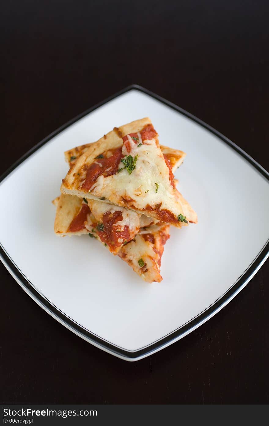 Small slices of plain pizza stacked on a white plate. A quick easy lunch. Small slices of plain pizza stacked on a white plate. A quick easy lunch.