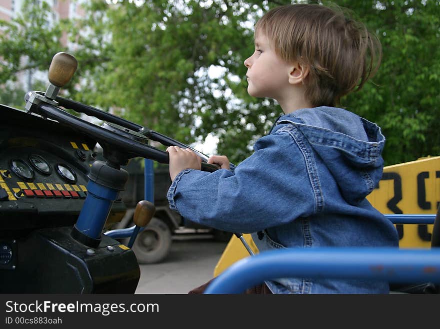 The small child would like to play with real road roller and want to look as the adult worker. The small child would like to play with real road roller and want to look as the adult worker