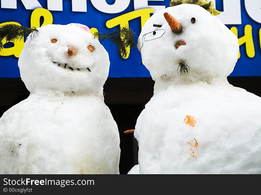 Two amusing snow-mans with glasses and carrots