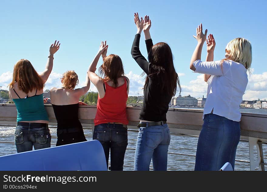 Five happy girls dancing on a boat