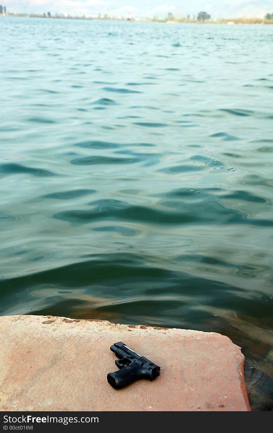 A toy pistoy on a stone in a lake. A toy pistoy on a stone in a lake