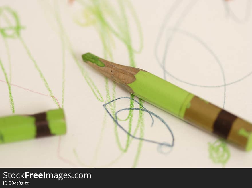 Crayons lie on a child's drawing. Crayons lie on a child's drawing