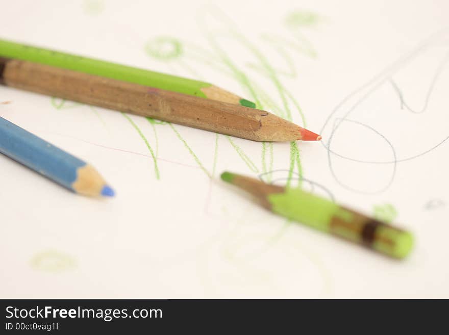 Crayons lie on a child's drawing. Crayons lie on a child's drawing