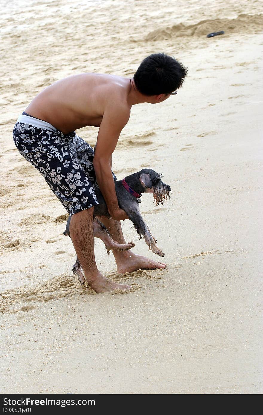 The man holding a wet dog (fox terrier) on the beach. The man holding a wet dog (fox terrier) on the beach