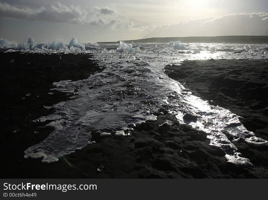 Wave and ice receeding on the black sand beach Iceland