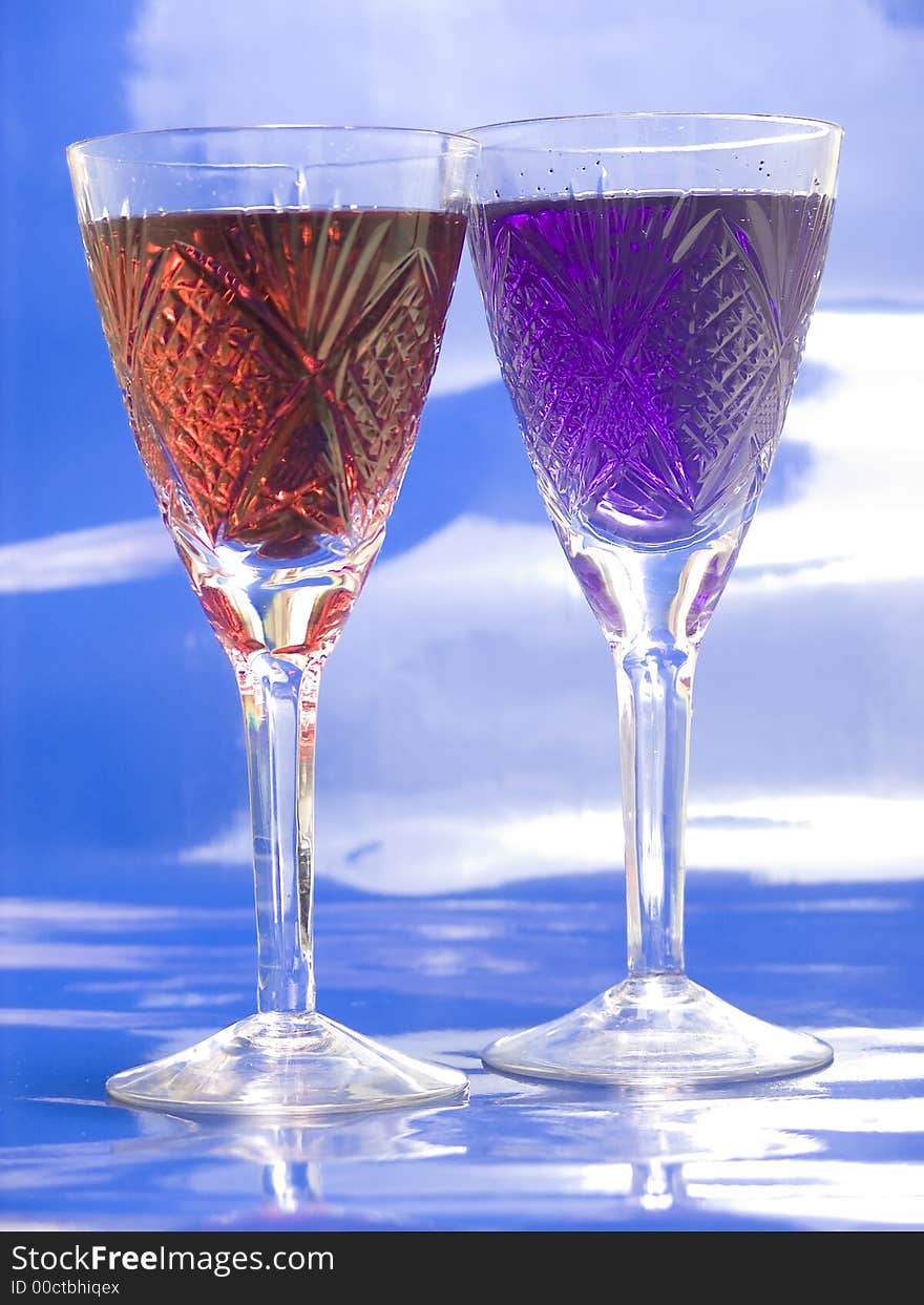 Tall glasses with red and blue  drinks on blue background. Tall glasses with red and blue  drinks on blue background