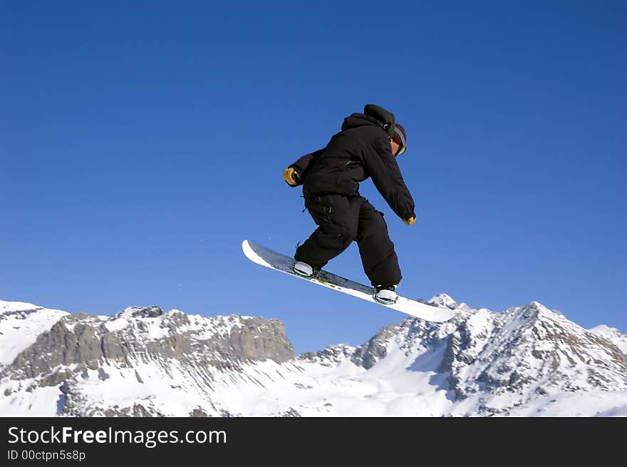 A snowboarder jumping high through a blue sky. A snowboarder jumping high through a blue sky