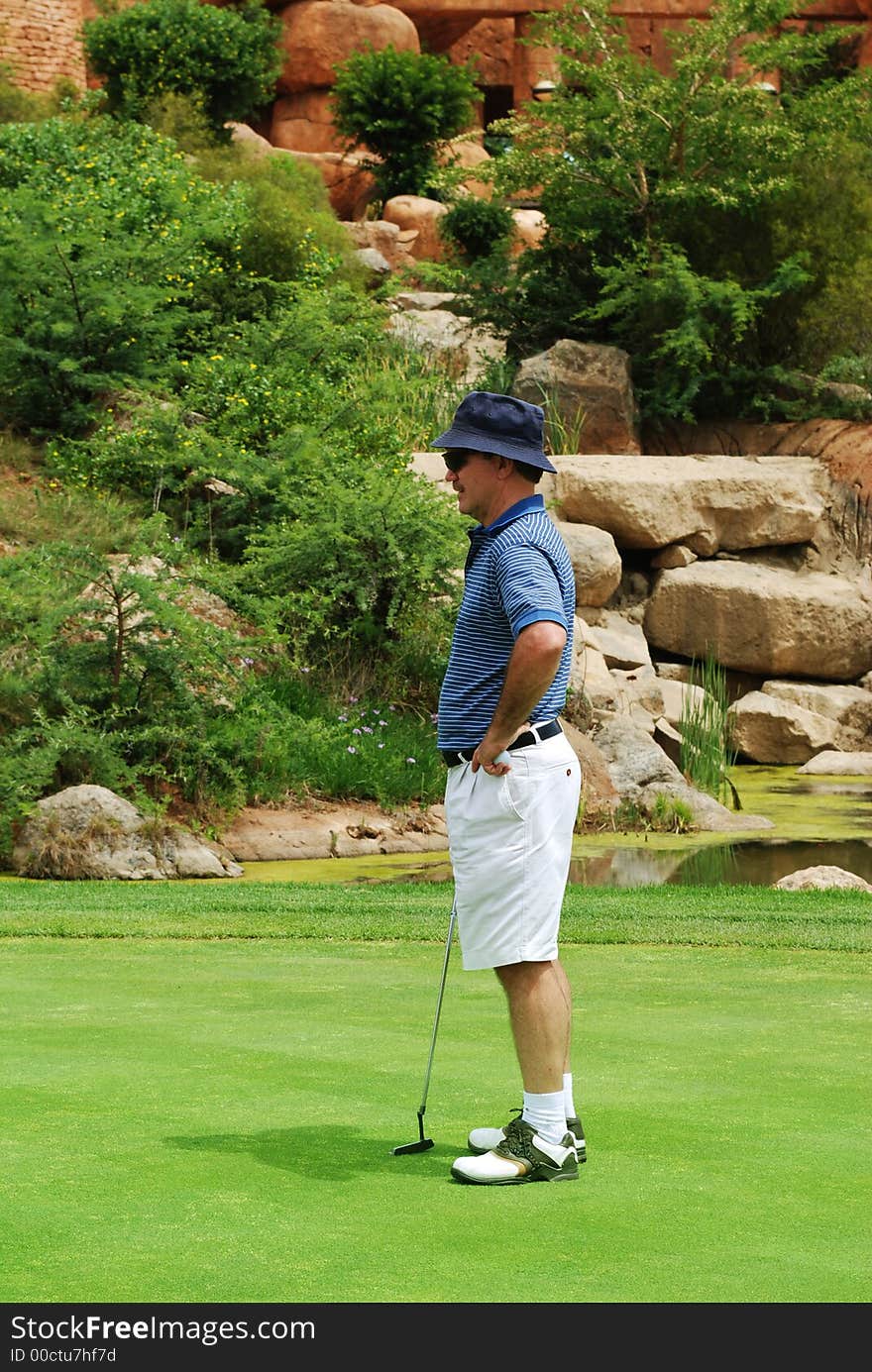 Middle age golfer evaluating the putt on the green. Middle age golfer evaluating the putt on the green.