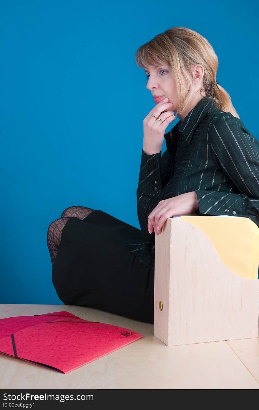 A thinking woman sorting through folders whilst sitting on a table