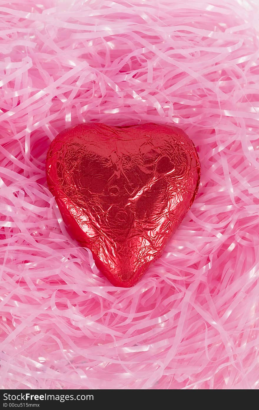 A foil-wrapped chocolate heart in pink easter hay