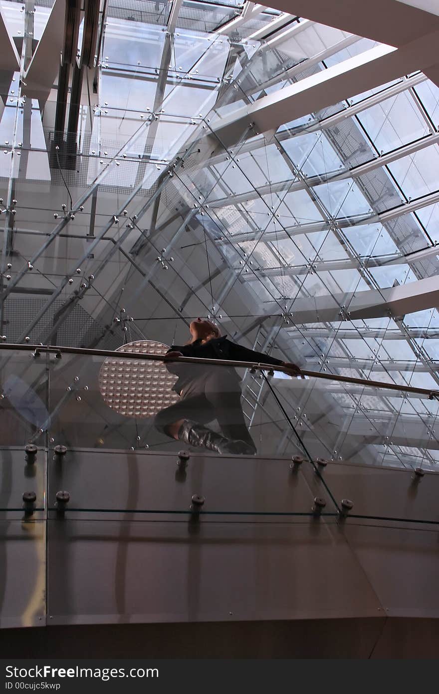 A man is sitting inside of a modern glassy edifice. A man is sitting inside of a modern glassy edifice