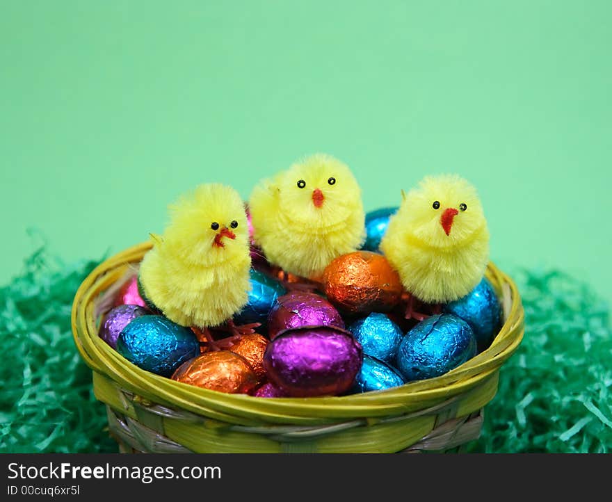 Coloured sweet  easter eggs and three chicken in grass  on green background