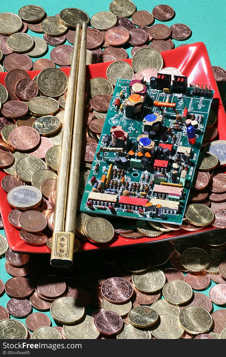 Red plate overboarding with coins,on top of them an integrated circuit and japanese eating.sticks. Red plate overboarding with coins,on top of them an integrated circuit and japanese eating.sticks.