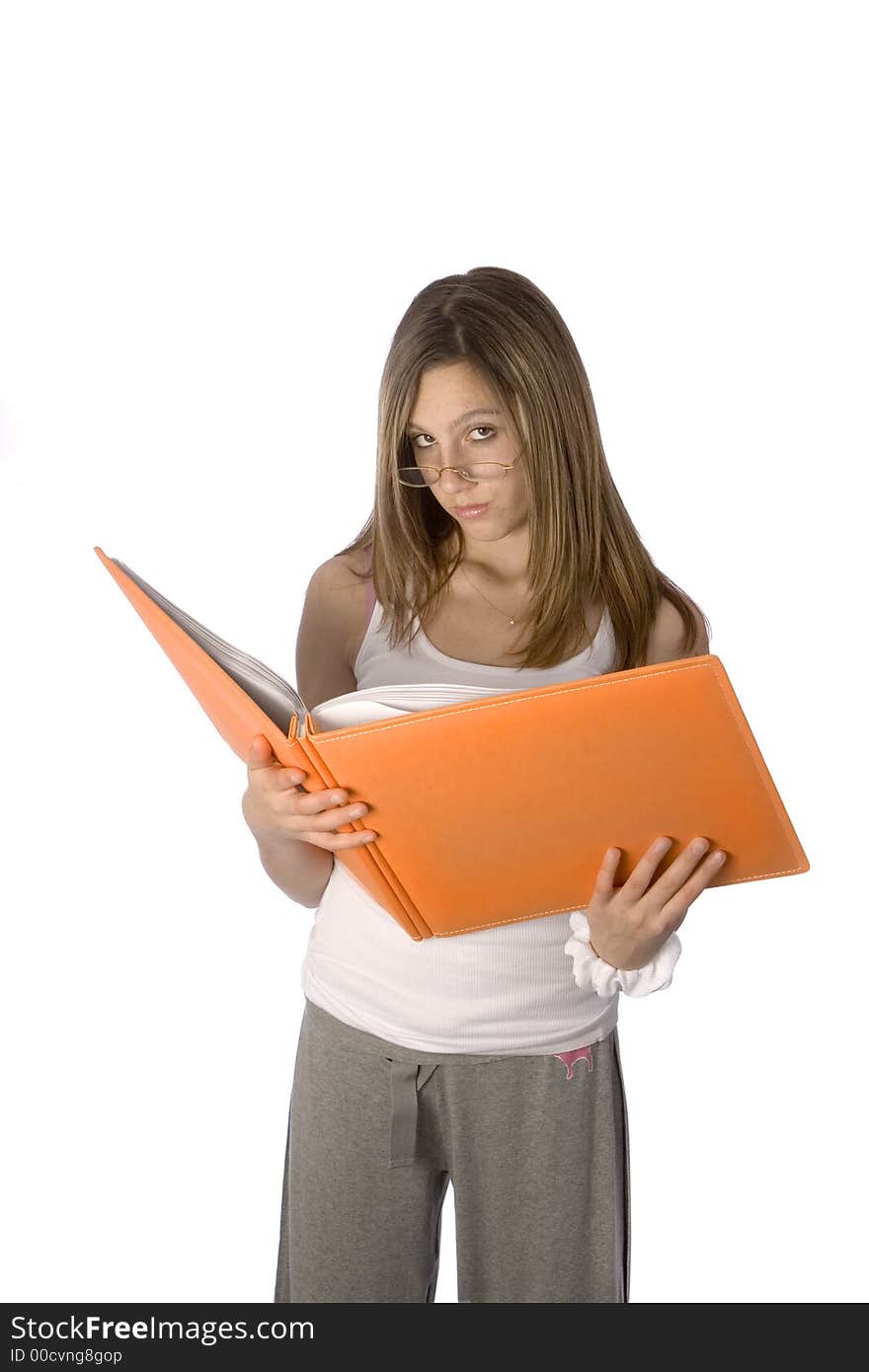 Teenager looking up from orange book with glasses on, no smile. Teenager looking up from orange book with glasses on, no smile