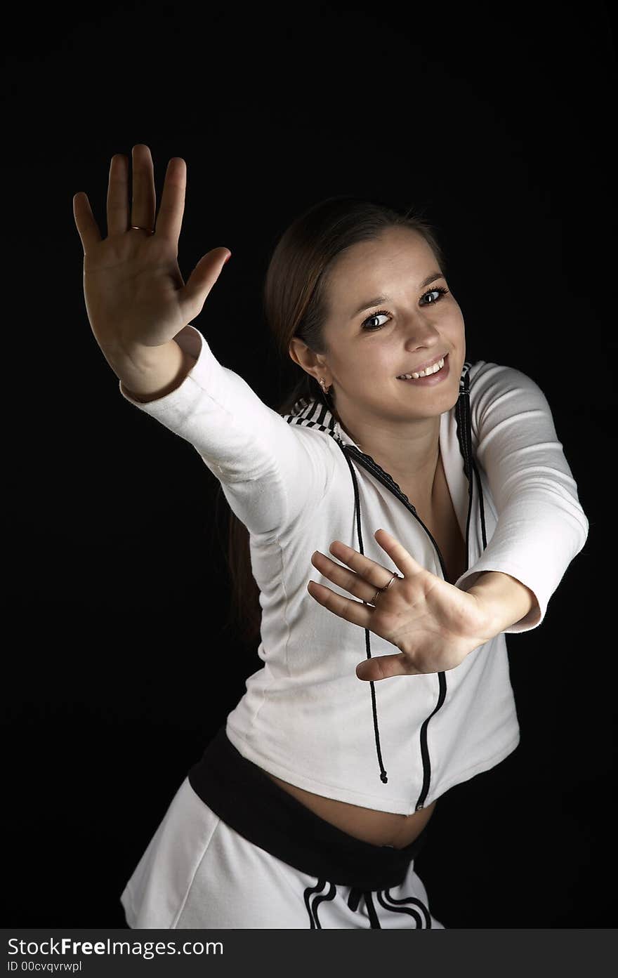 Girl with raised hands in white sportive wear on black background. Girl with raised hands in white sportive wear on black background