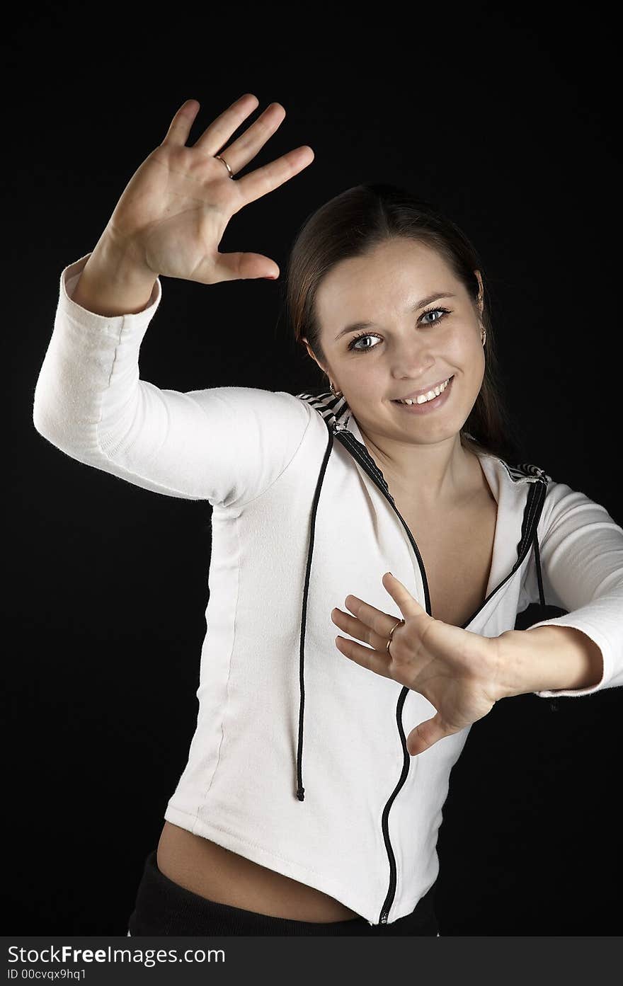 Smiling girl with raised hands in white sportive wear on black background. Smiling girl with raised hands in white sportive wear on black background