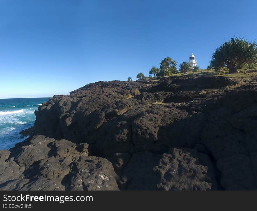 A white lighthouse and rock cliff