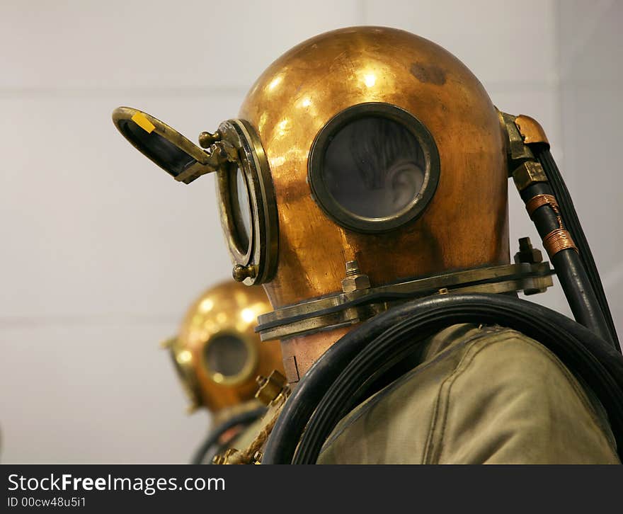 Two mannequin are dressed in diving suits with round copper helmets