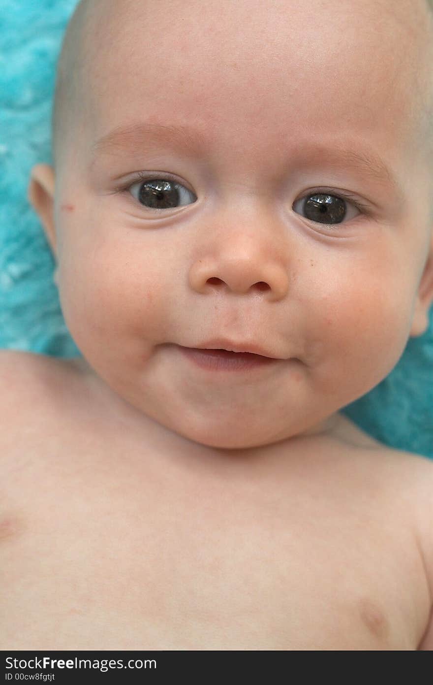 Image of cute smiling baby lying on a turquoise blanket. Image of cute smiling baby lying on a turquoise blanket