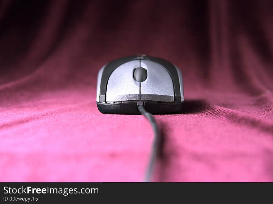 Computer mouse of grey color on purple velvet background