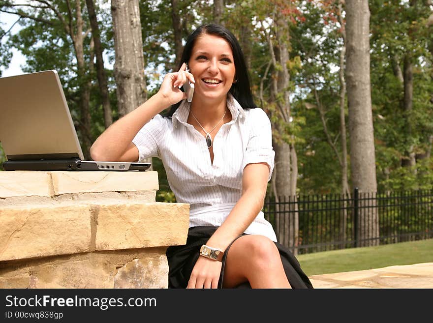 Young woman using a laptop and cell phone to network. Young woman using a laptop and cell phone to network