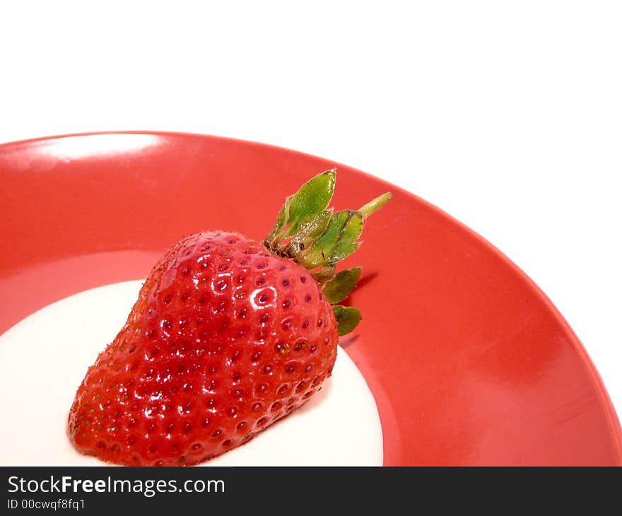 One fresh strawberry with cream on red plate. One fresh strawberry with cream on red plate