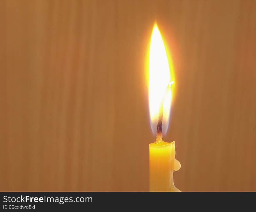 Burning candle at the brown background . Burning candle at the brown background