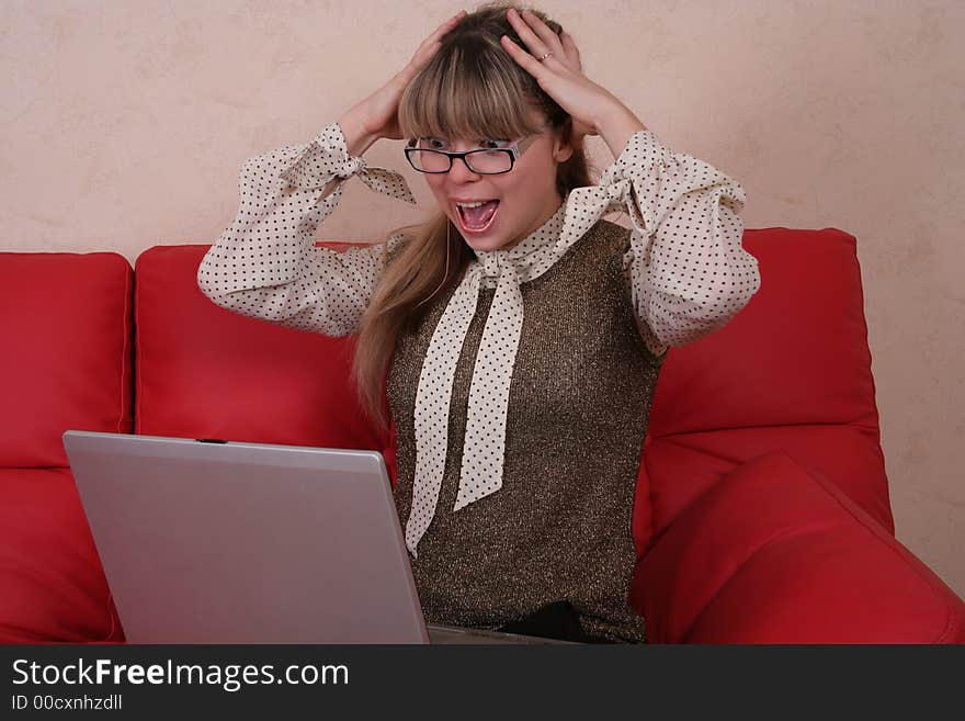 Amazed woman with laptop on red sofa. Amazed woman with laptop on red sofa