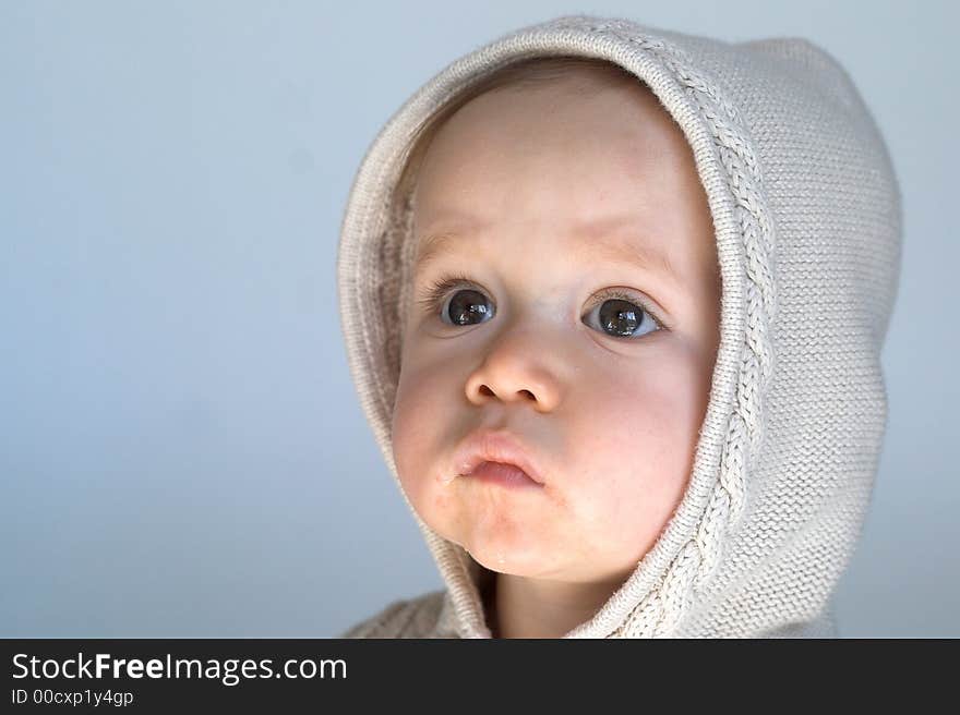 Image of cute baby wearing a hooded sweater, sitting in front of a white background. Image of cute baby wearing a hooded sweater, sitting in front of a white background