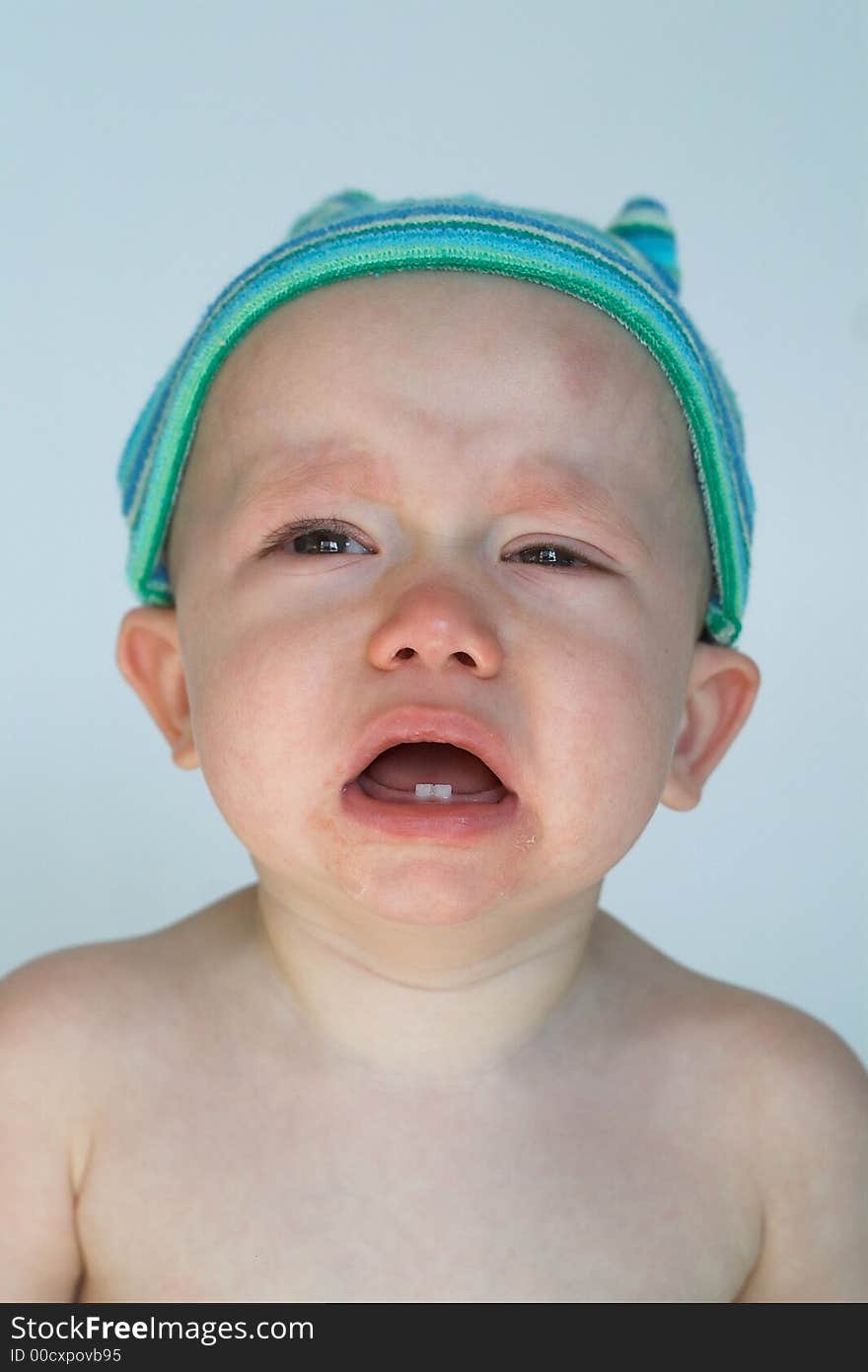 Image of crying baby sitting in front of a white background