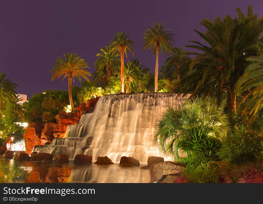 This is a waterfall surrounded by palm trees and a little lake