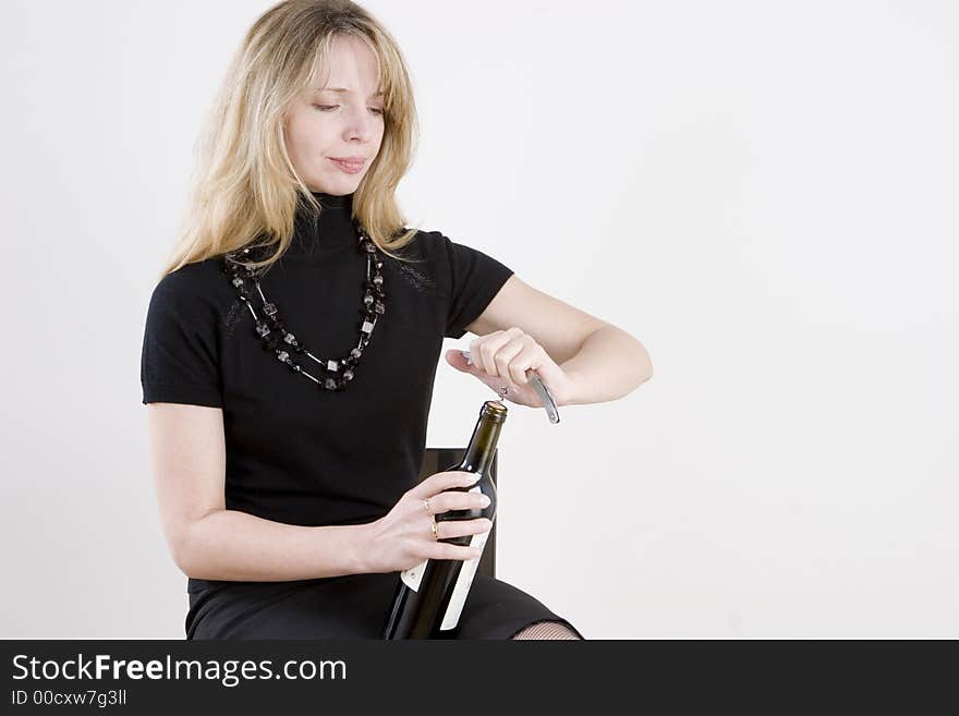 A woman opening a bottle of red wine. A woman opening a bottle of red wine