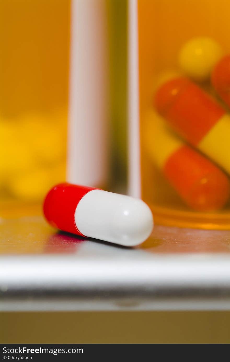 Close up photograph of a medication capsil on a medicine cabinet sil. Close up photograph of a medication capsil on a medicine cabinet sil.