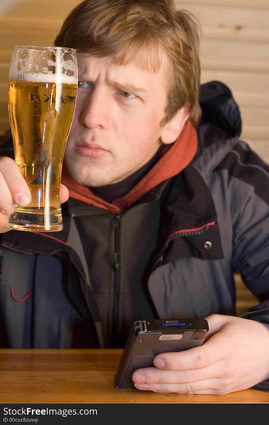 Man looking at beaker of beer and holding palm-size computer.