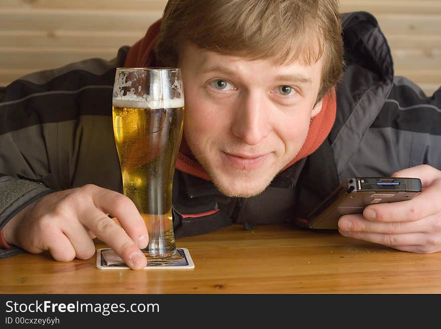 Man with beaker of beer and palm-size computer. Smiling. Man with beaker of beer and palm-size computer. Smiling