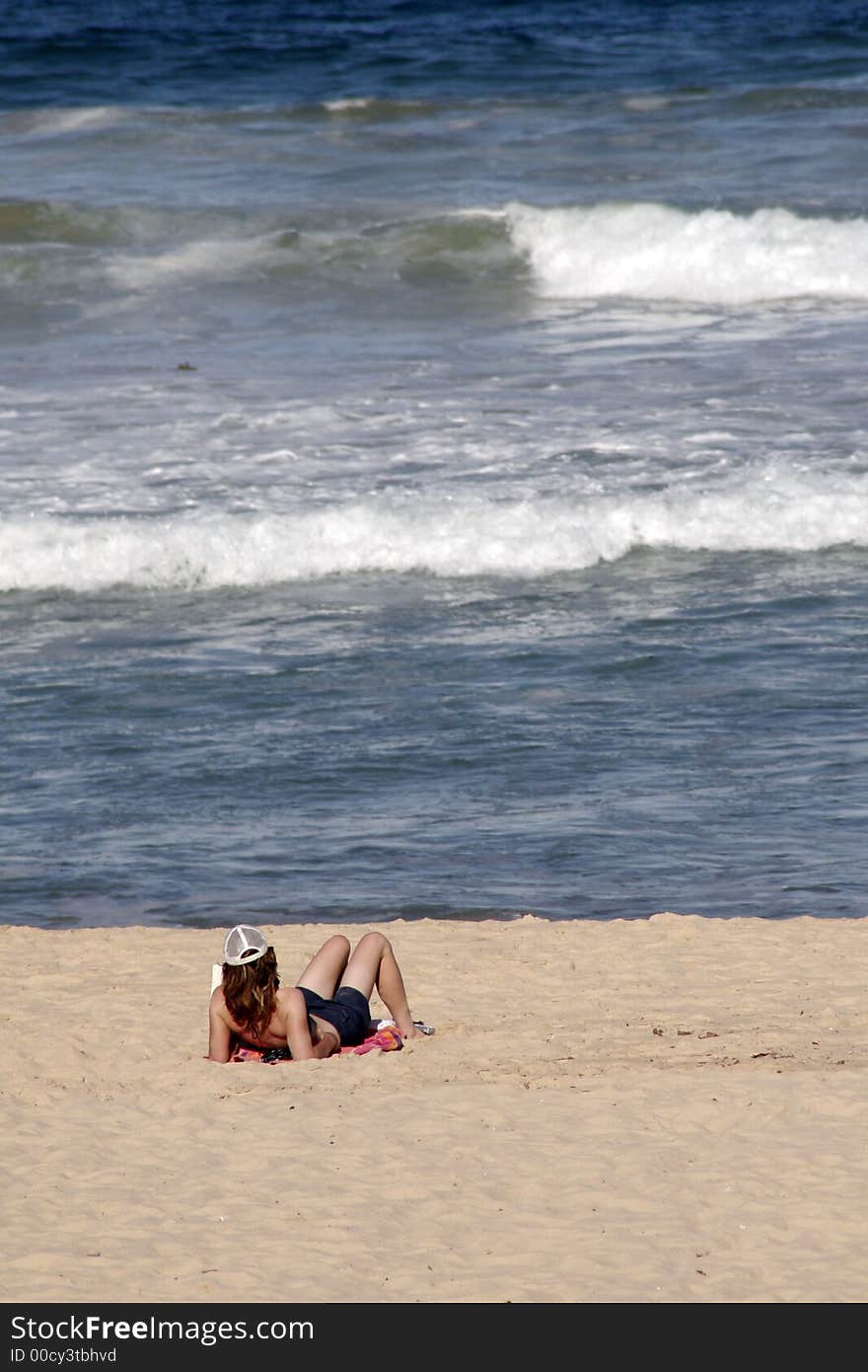 Girl At A Sandy Beach Reading A Book And Looking At The Ocean Waves. Girl At A Sandy Beach Reading A Book And Looking At The Ocean Waves