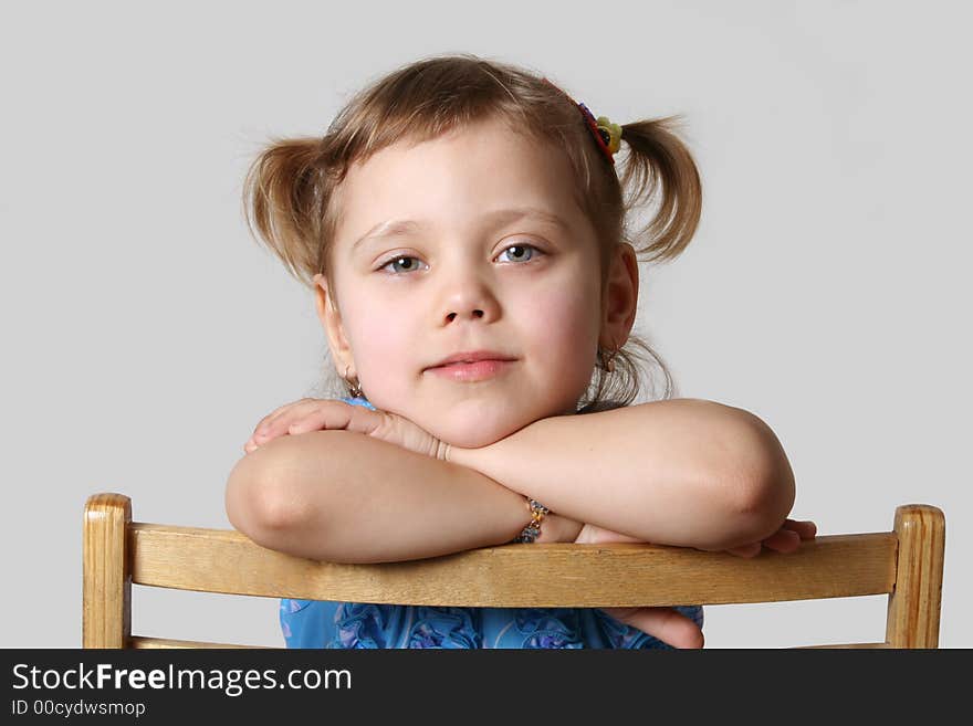 Small girl sits on chair, gray background. Small girl sits on chair, gray background