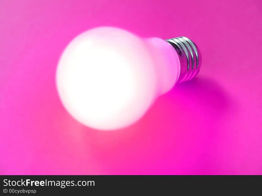 Illuminated lightbulb on magenta background